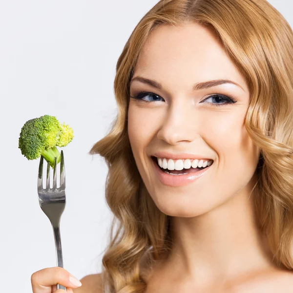 Woman eating broccoli, over gray — Stock Photo, Image