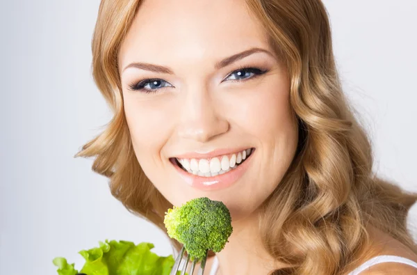 Žena jíst brokolici, nad šedá — Stock fotografie