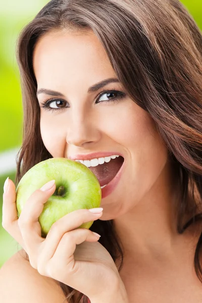 Mujer joven comiendo manzana, al aire libre — Foto de Stock