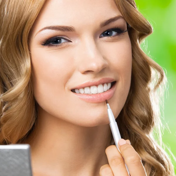 Mujer sonriente con cepillo de maquillaje, al aire libre —  Fotos de Stock