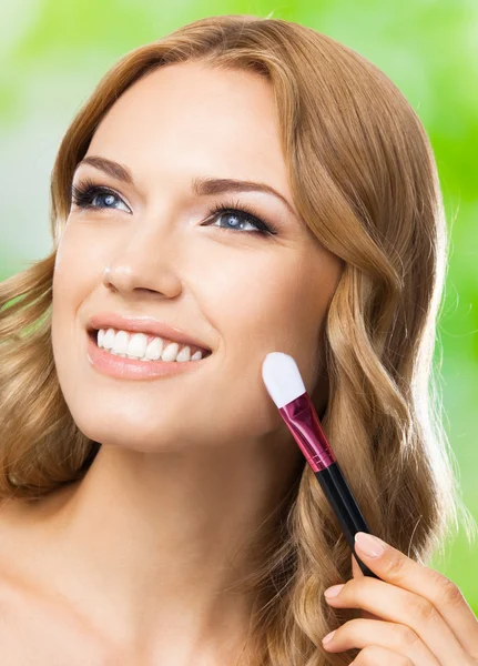 Smiling woman with make up brush, outdoor — Stock Photo, Image