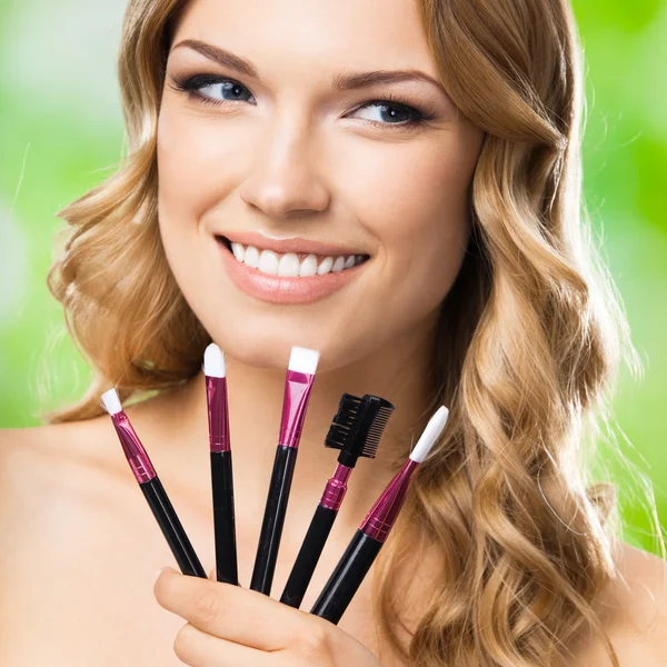 Mujer sonriente con herramientas de maquillaje, al aire libre —  Fotos de Stock