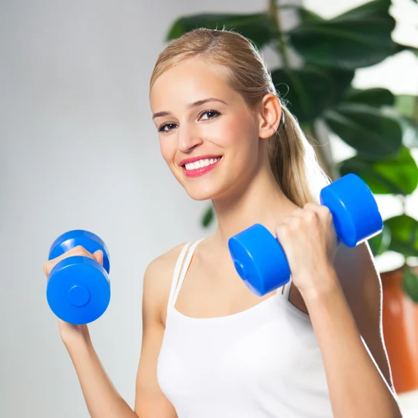 Junge glücklich lächelnde Frau mit Hanteln, drinnen — Stockfoto