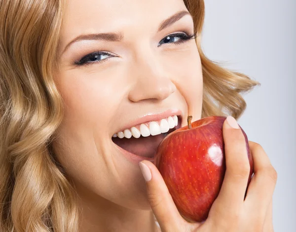 Frau isst Apfel, auf grau — Stockfoto