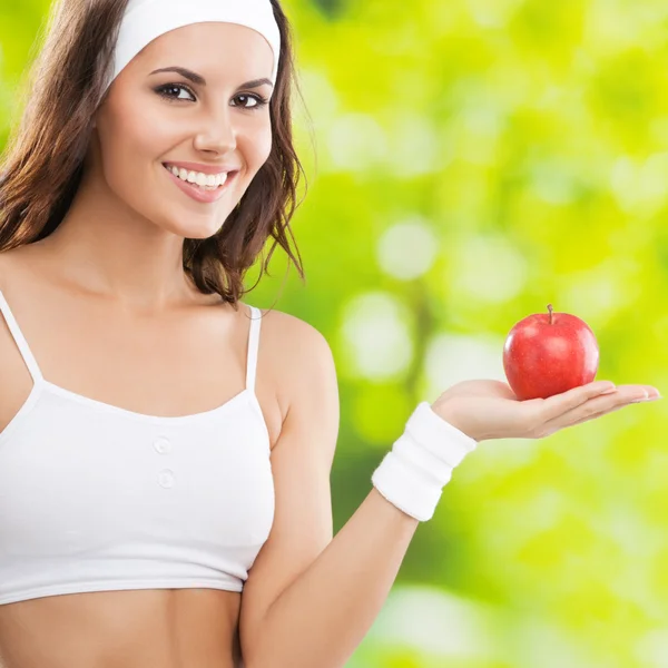 Mujer en ropa de fitness con manzana, al aire libre —  Fotos de Stock