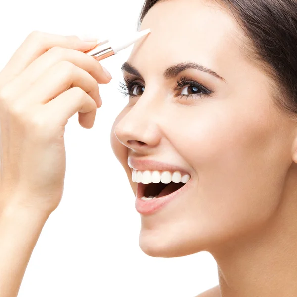 Smiling woman applying concealer on face, isolated — Stock Photo, Image