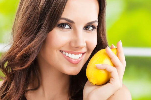 Молодая счастливая улыбающаяся женщина с лимоном, на открытом воздухе — стоковое фото