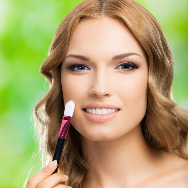 Mujer sonriente con cepillo de maquillaje, al aire libre — Foto de Stock