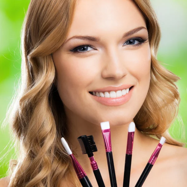 Mujer sonriente con herramientas de maquillaje, al aire libre —  Fotos de Stock