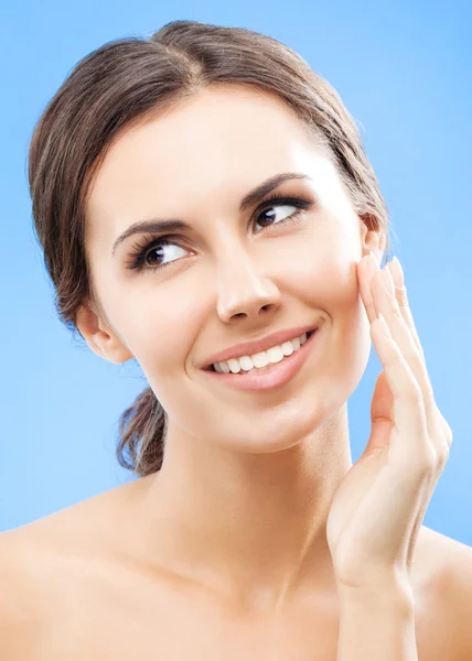 Woman touching skin or applying cream, over blue — Stock Photo, Image