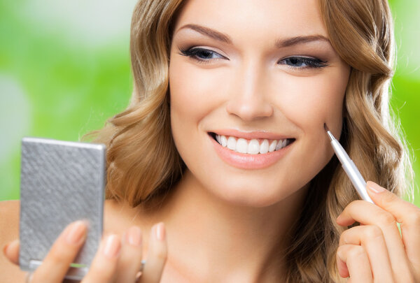 Smiling woman with make up brush, outdoor