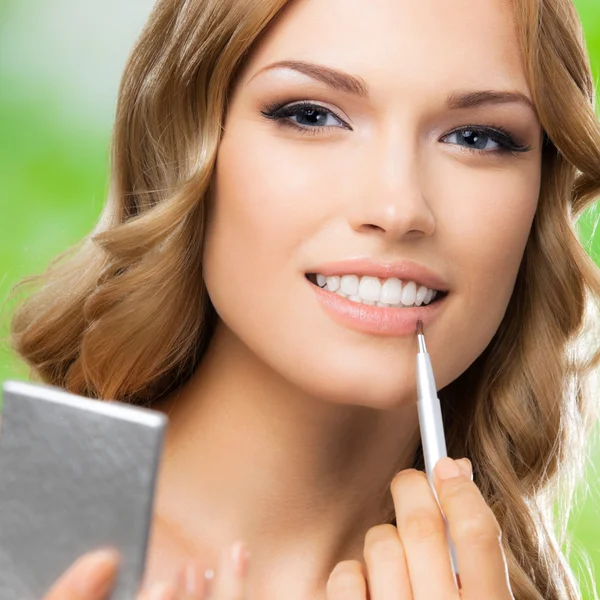 Mujer sonriente con cepillo de maquillaje, al aire libre — Foto de Stock