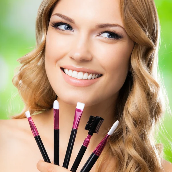 Mujer sonriente con herramientas de maquillaje, al aire libre —  Fotos de Stock