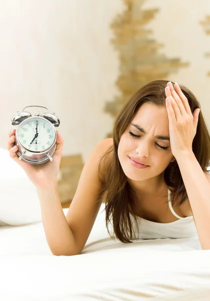 Vrouw met alarmclock op het bed — Stockfoto