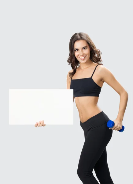 Woman in fitnesswear showing signboard, over grey — Stock Photo, Image