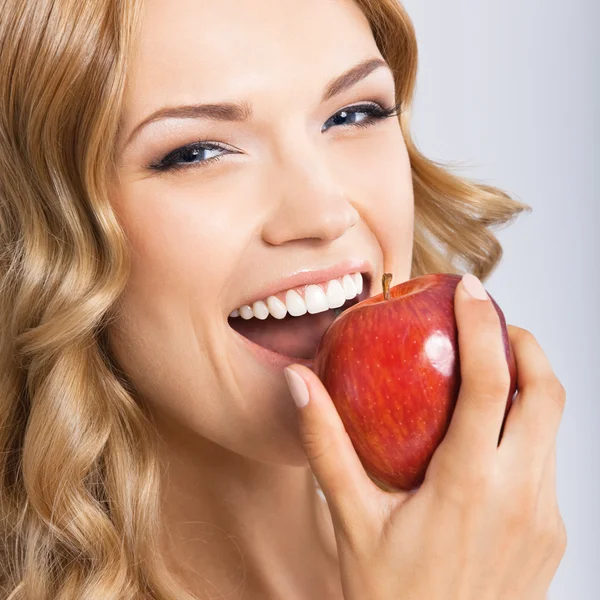 Frau isst Apfel, auf grau — Stockfoto