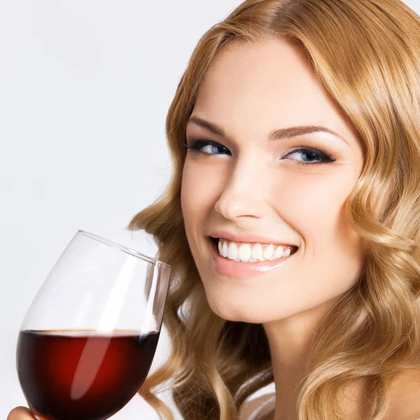 Jeune femme heureuse avec un verre de vin rouge, sur gris — Photo