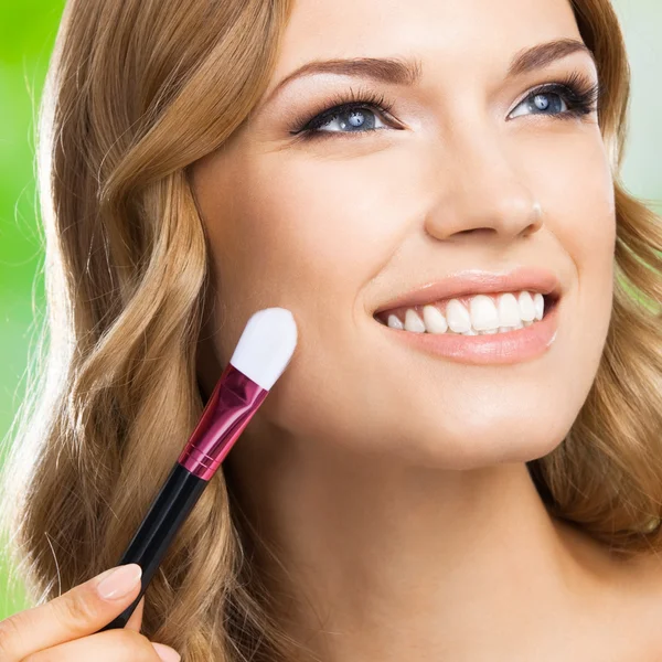 Lächelnde Frau mit Make-up Pinsel, im Freien — Stockfoto