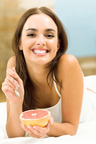 Portarit of young woman eating grapefruit at home — Stock Photo, Image