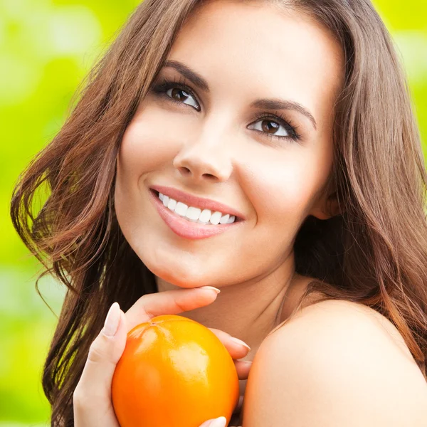 Young woman with persimmon fruit, outdoors — Stock Photo, Image