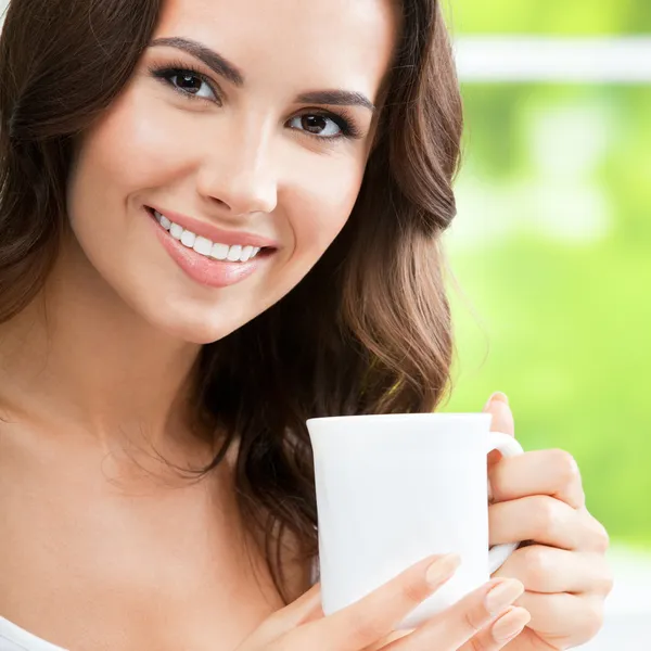 Ung kvinna dricker kaffe eller te, hemma — Stockfoto