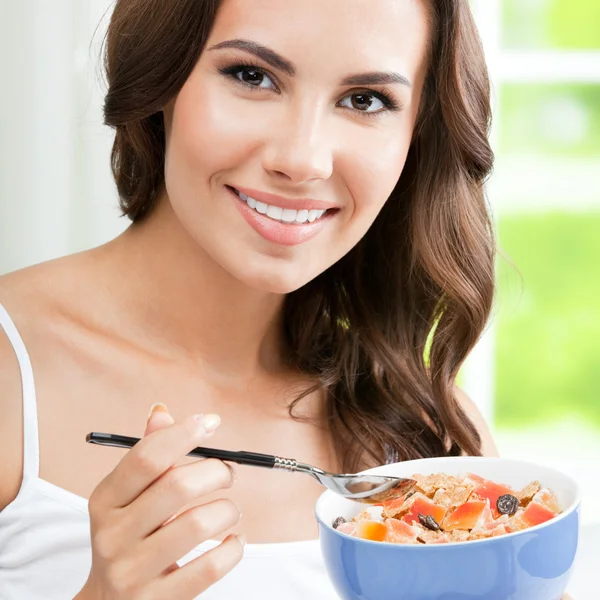 Fröhliche schöne Frau isst Musselin, drinnen — Stockfoto