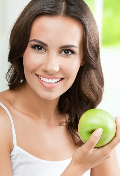 Joven mujer sonriente feliz con manzana, en el interior — Foto de Stock