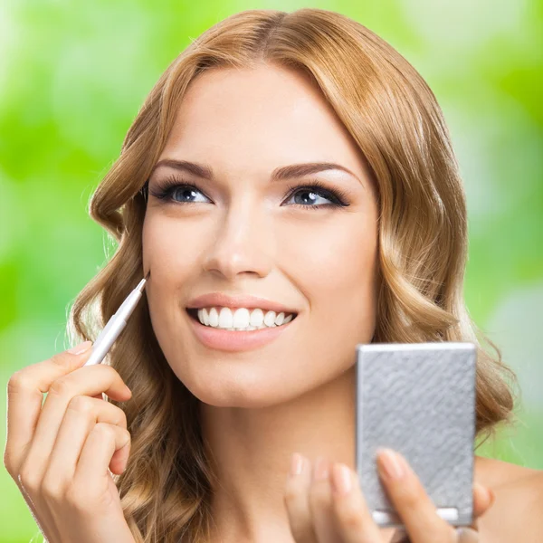 Mujer sonriente con cepillo de maquillaje, al aire libre —  Fotos de Stock