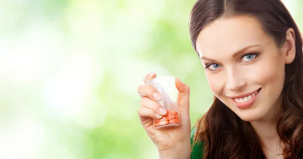 Женщина показывает бутылку с таблетками, на открытом воздухе — стоковое фото