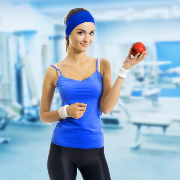 Женщина в спортивной одежде с яблоком, в спортзале — стоковое фото