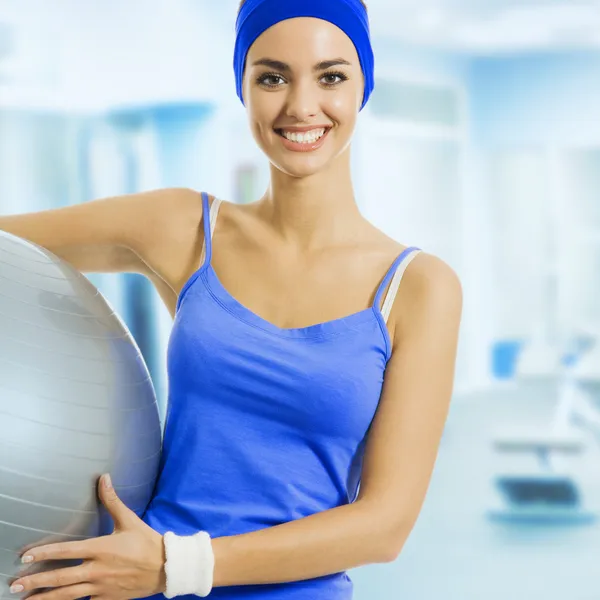 Jovem mulher feliz com bola de fitness, no ginásio — Fotografia de Stock