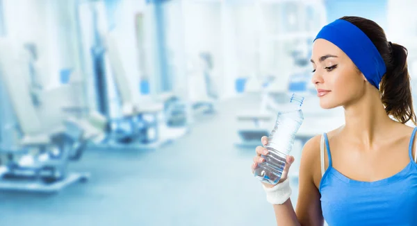 Mujer en ropa deportiva agua potable, en el gimnasio — Foto de Stock