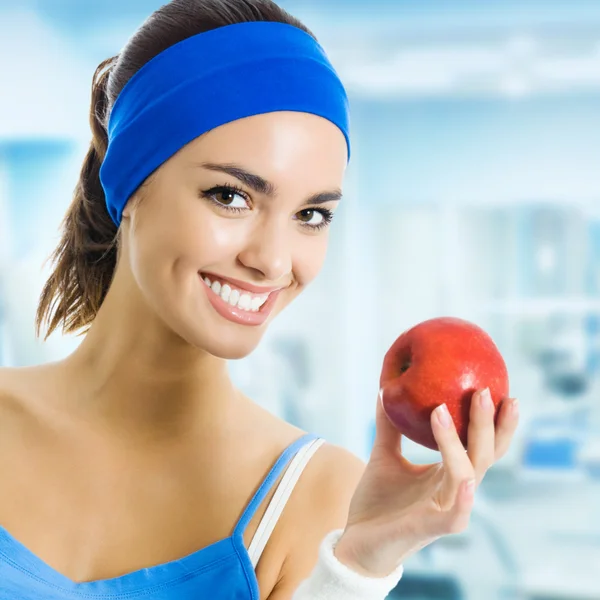 Mujer en ropa deportiva con manzana, en el gimnasio —  Fotos de Stock