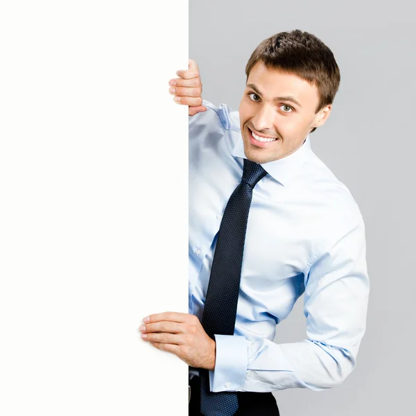 Ο άνθρωπος των επιχειρήσεων δείχνει κενό πινακίδα, πέρα από το γκρι — Φωτογραφία Αρχείου