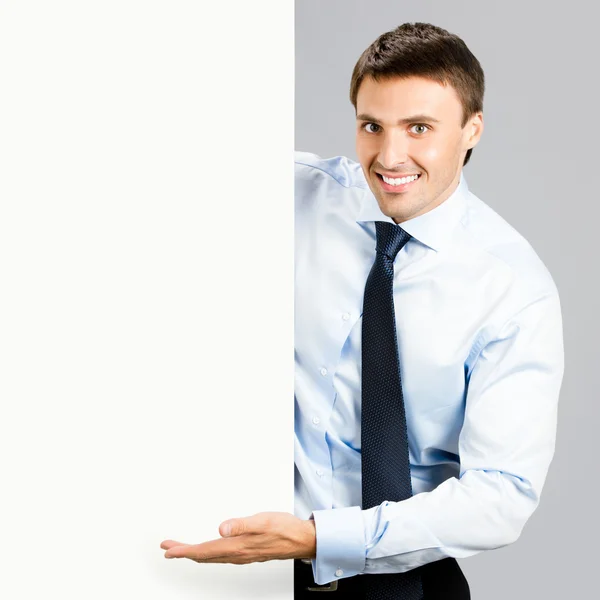 Ο άνθρωπος των επιχειρήσεων δείχνει κενό πινακίδα, πέρα από το γκρι — Φωτογραφία Αρχείου