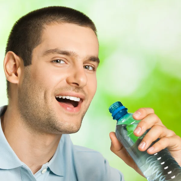 Jonge lachende man drinkwater, buitenshuis — Stockfoto