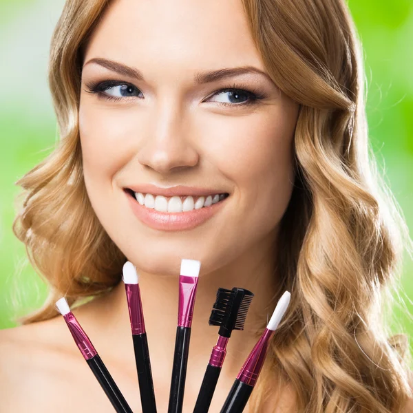 Mujer sonriente con herramientas de maquillaje, al aire libre —  Fotos de Stock