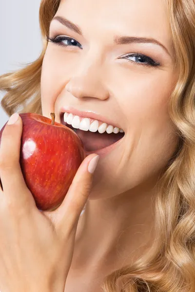 Woman eating apple, on grey Royalty Free Stock Images