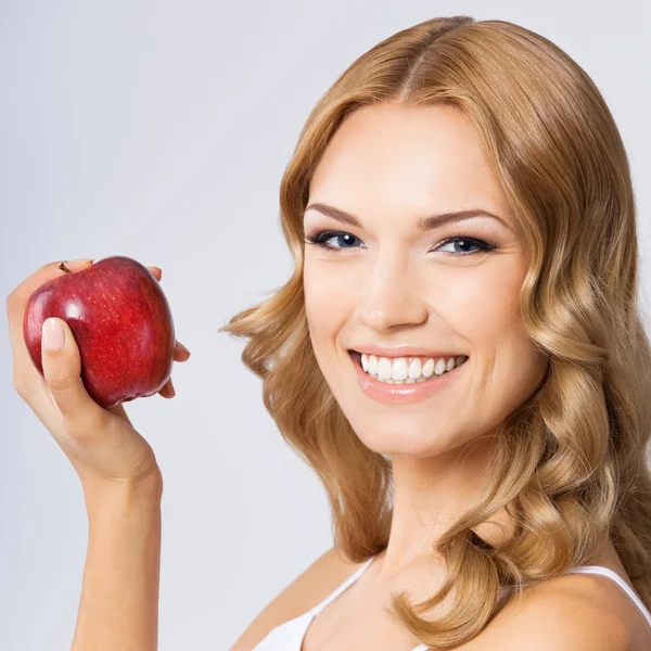Жінка з яблуком, на сірому — стокове фото