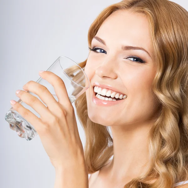 Jonge vrouw drinken van water, op grijs — Stockfoto
