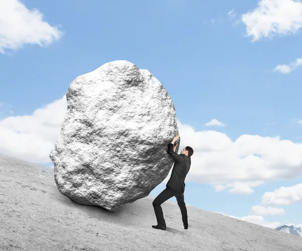 Hombre de negocios empujando piedra — Foto de Stock