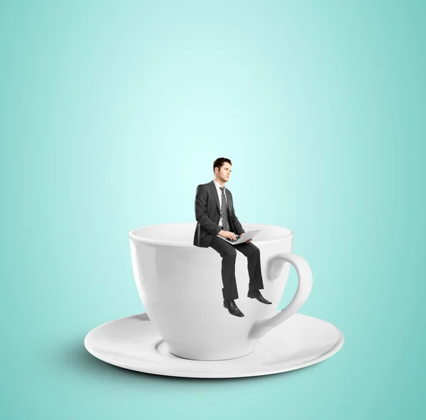 Businessman sitting on cup — Stock Photo, Image