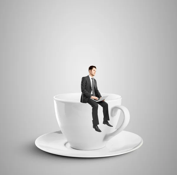 Бизнесмен, сидящий на чашке — стоковое фото