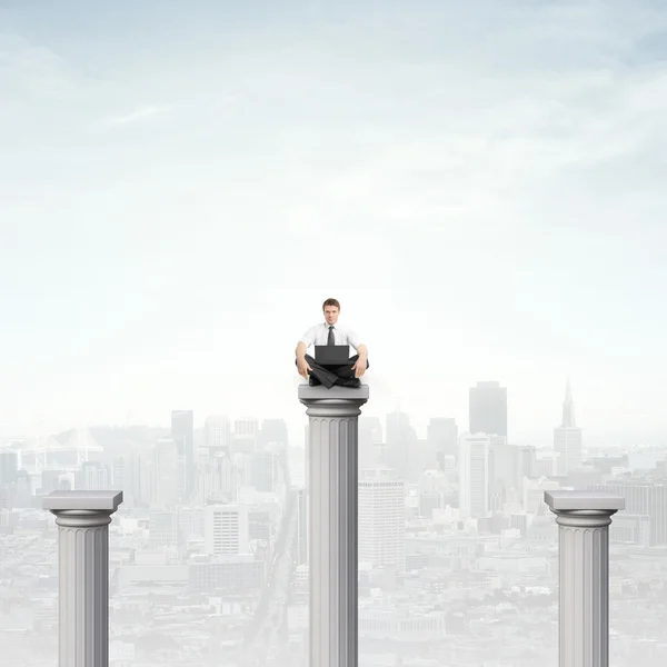 Businessman sitting on column — Stock Photo, Image