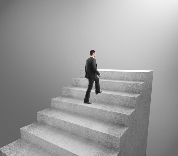 Businessman climbing to stairs on gray background