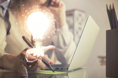 Bilgisayarda yazı yazan ve ampul çizen bir kadının ellerine iki kez maruz kalmış. Fikir kavramı.