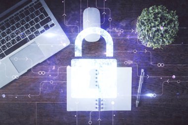 Bilgisayarla çalışma masası arkaplanının üzerine iki kat kilit hologramı çiziliyor. Veri güvenliği kavramı. Üst görünüm.