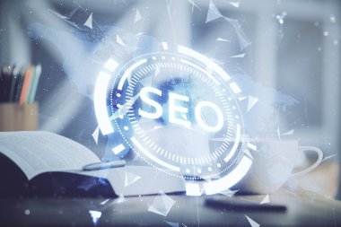 SEO yazılarını ve masaüstünü kahve ve masa arkasında eşyalar eşliğinde iki kez görüntüle. Arama optimizasyonu kavramı.