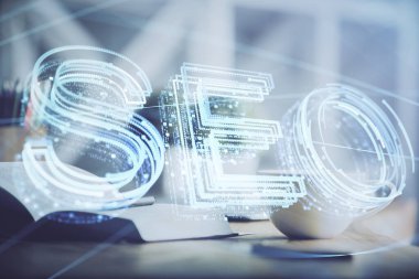 SEO yazılarını ve masaüstünü kahve ve masa arkasında eşyalar eşliğinde iki kez görüntüle. Arama optimizasyonu kavramı.