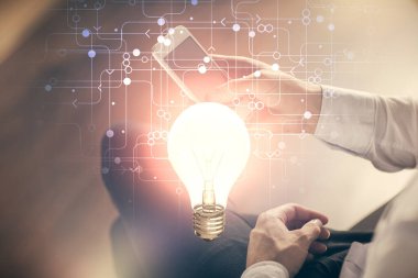 Dijital bir cihaz ve ampul hologram çizimi kullanarak insanın ellerini tutarken çift pozlama. Fikir kavramı.